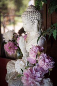 Wesak flowers Buddha in gassho photo by Alyson Levy Wallowa Buddhist Temple porch