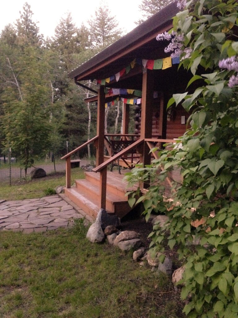 Wallowa Buddhist Temple front porch steps at Wesak lilac blooms prayer flags stone walkway